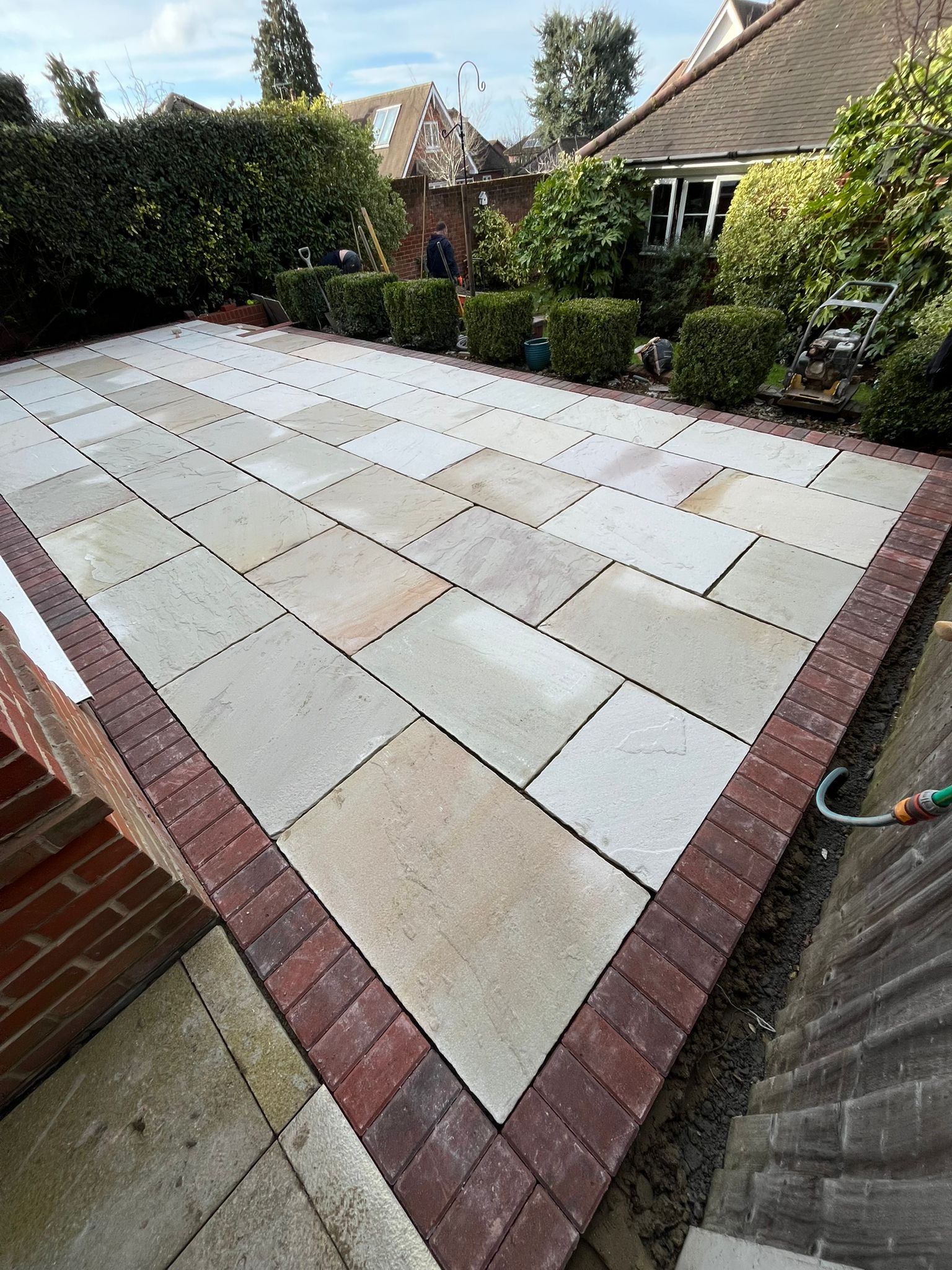 Indian sandstone patio with brick soldier-course border