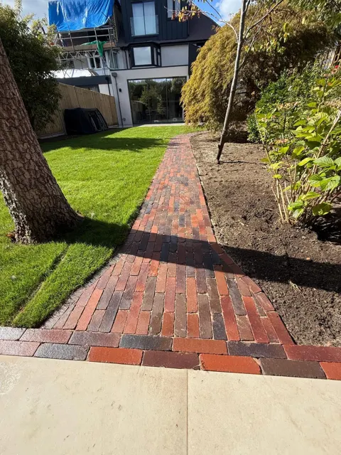 Red brick garden path through planted borders