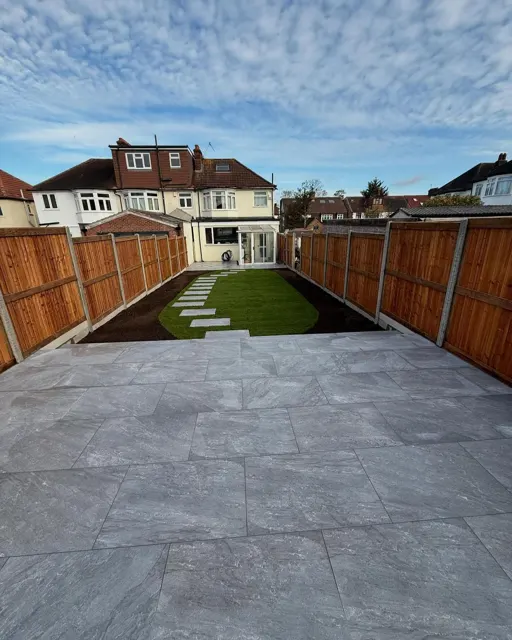 Grey paved garden with lawn and close-board fencing