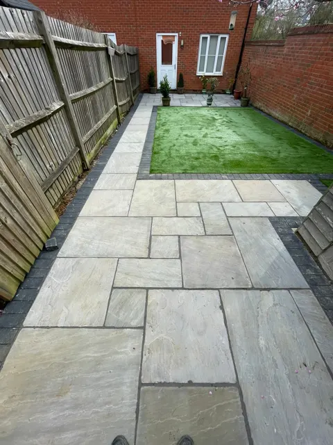 Grey natural stone patio next to artificial grass