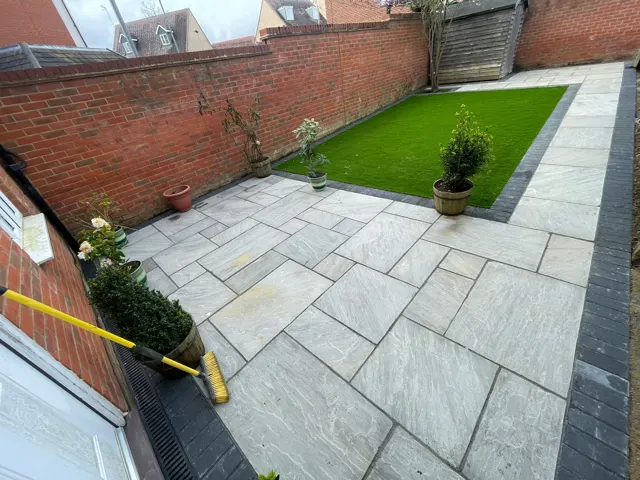 Grey paving patio with artificial grass in a back garden