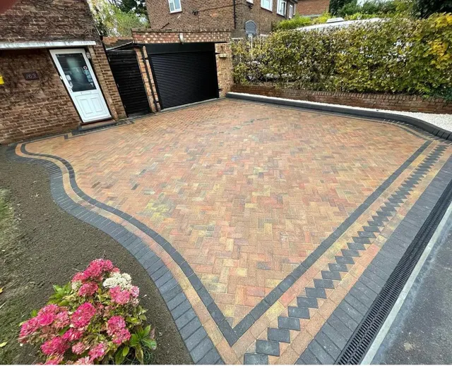 Buff block paving driveway with curved border and planting
