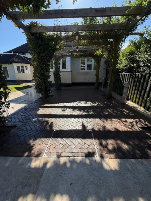 Dark block paved garden patio with pergola